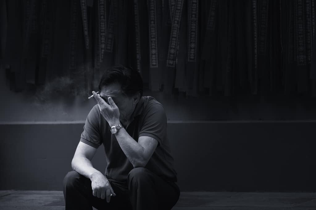 Grief Black-and-white photo of a man sitting alone with his head in his hand