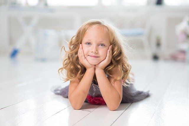 Relaxed and happy Smiling girl lying on the floor with her chin in her hands