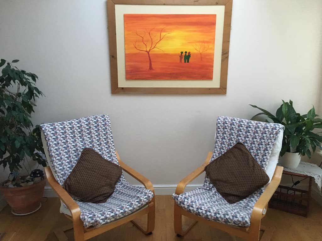 Two armchairs in Sonya Hudson's therapy room beneath a sunset painting