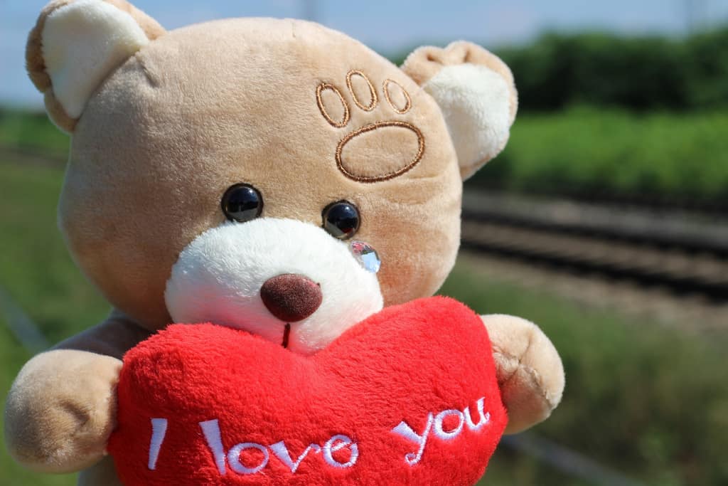 Love and relationships Teddy bear holding a red I love you heart by a railway