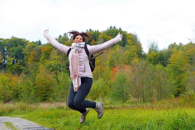 Letting go Woman jumping for joy in a meadow