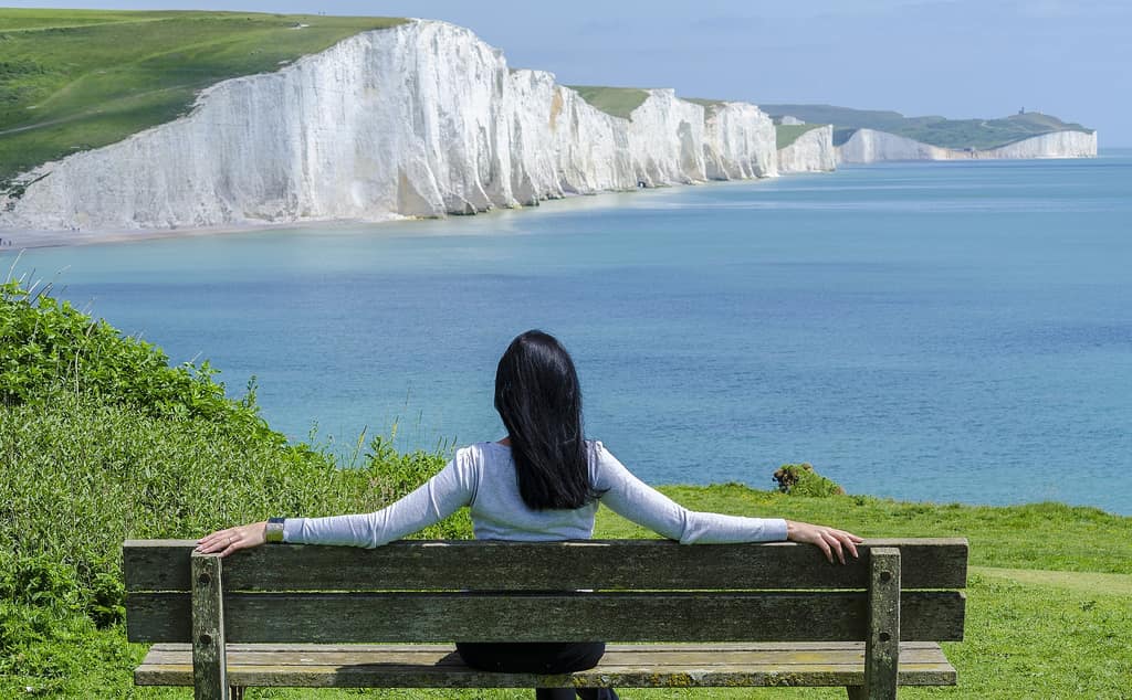 Woman on a bench overlooking white chalk cliffs and the sea