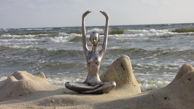 Balance Metal statue of a figure in a yoga pose on a beach